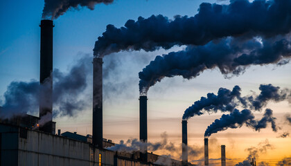 Industrial factory smokestacks emitting dark smoke into the sky.