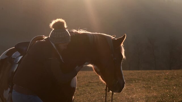 Young woman affectionately cuddling her Haflinger mix pinto mare outdoors, showing trust, friendship and calm bond
