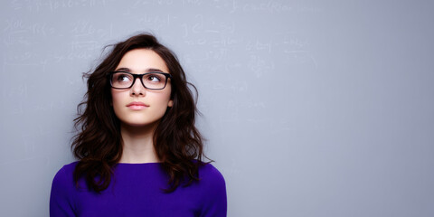 Young female notebook top violet woman girl brunette hair goggles student daydream in front of chalkboard with math formula faintly visible on wall background