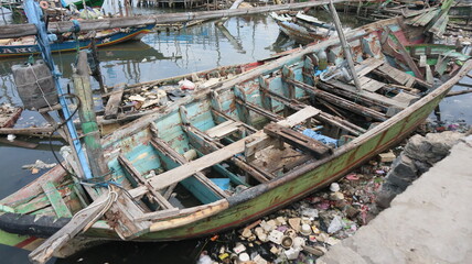 A damaged traditional fishing boat that sits at the estuary towards the beach. This boat is usually used by fishermen to catch fish in the middle of the sea.
