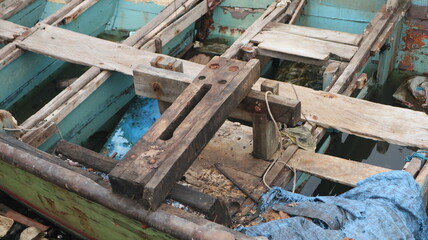 A damaged traditional fishing boat that sits at the estuary towards the beach. This boat is usually used by fishermen to catch fish in the middle of the sea.