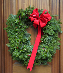 Decorative Christmas wreath made of natural evergeen branches on wood grain door