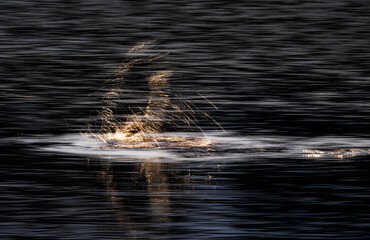 Abstract long exposure water light trails and golden splash on dark lake creating cinematic portal illusion motion blur reflections and minimalist fine art mood of time and transformation at dusk