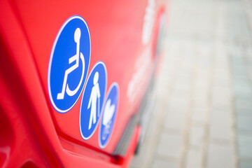 Signs for disability accessible on a red bus in a city setting