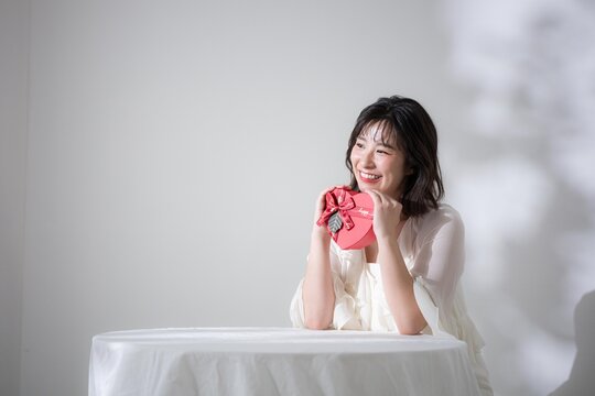バレンタインやプレゼントを笑顔で持つ女性　告白やイベントやギフトなど贈り物のイメージ全身