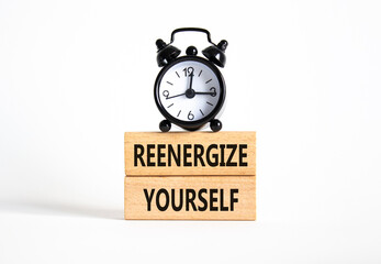Reenergize yourself symbol. Concept words Reenergize yourself on wooden blocks. Beautiful white background with alarm clock. Mindfulness and Reenergize yourself concept. Copy space.