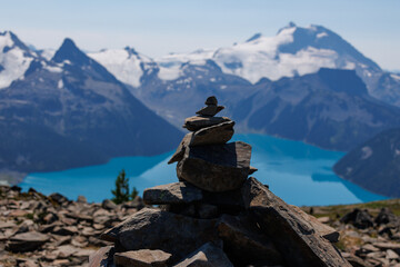 A pyramid made of stones against the backdrop of a blue lake and snow-capped mountains.