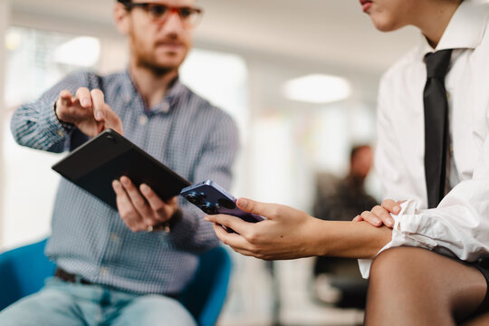 Business professionals collaborate in a modern office setting using digital devices to enhance productivity and communication during a meeting - Powered by Adobe
