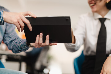 Business professionals collaborating on a digital project in a modern office setting during daytime, showcasing teamwork and communication skills