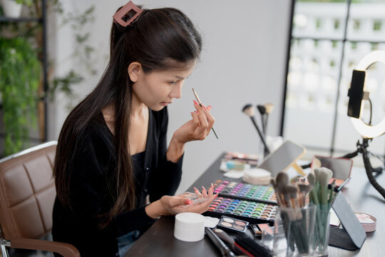 Asia woman beauty influencer makeup artist vlogger live streaming makeup tutorial on smartphone for social media