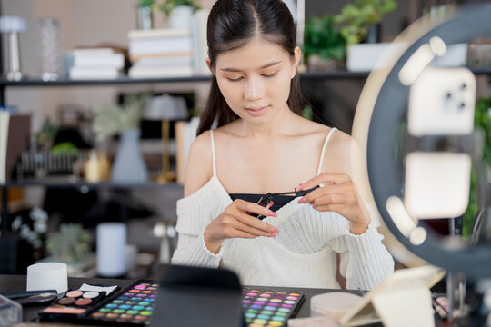 Asia woman beauty influencer makeup artist vlogger live streaming makeup tutorial on smartphone for social media - Powered by Adobe