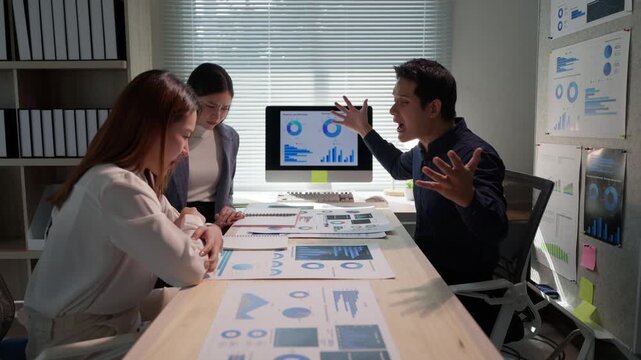 Stressful business meeting in the office at night. Angry boss shouting and blaming his two female employees for bad work results