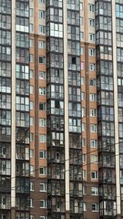 A close-up view of a modern residential building facade, featuring a mix of glass and brick elements, with numerous windows and balconies