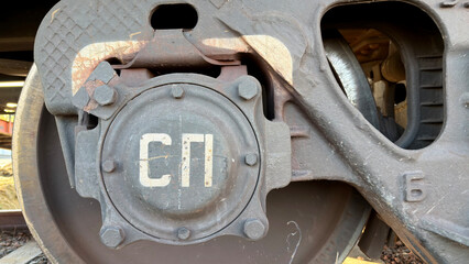 Close-up of a train wheel with a metal cover featuring Cyrillic letters