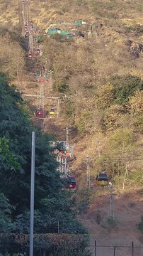 Pavagadh hill ropeway Gujarat India vertical shot showing multiple cable cars climbing forested mountain, popular pilgrimage and tourism transport connecting hilltop temple.