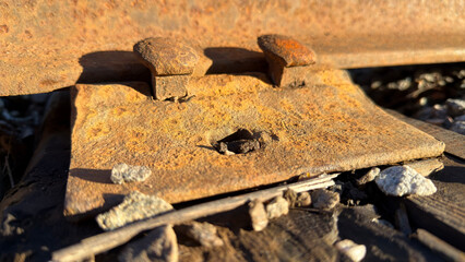 Close-up of rusty railroad track components on gravel