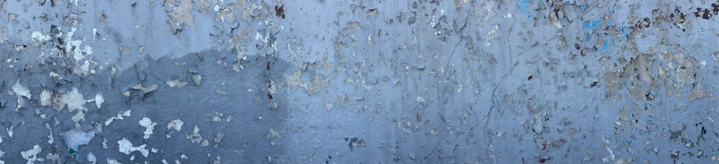 A textured wall with peeling paint in shades of blue and gray, showcasing layers of old paint and surface imperfections