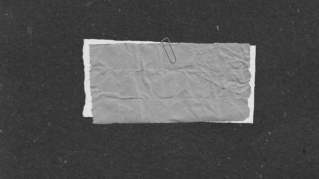 Crumpled paper with staple on black background abstract design in a grayscale aesthetic