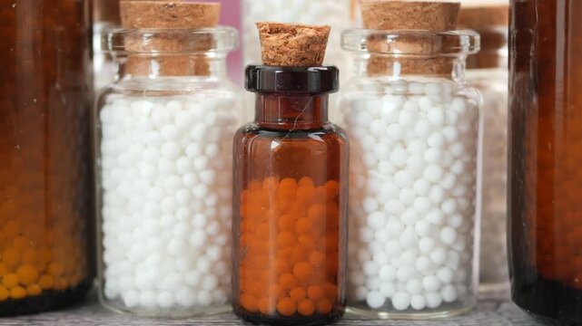 Homeopathy remedies in small glass jars on a table