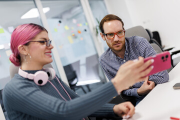 Business professionals collaborate in a modern office setting while discussing ideas using a smartphone during a team meeting