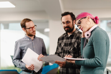 Businesspeople collaborating in a modern office setting while reviewing documents and discussing project details during the daytime