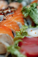 Mixed Sushi Set nigiri, rolls and sashimi served in traditional Japan black Sushioke round plate.