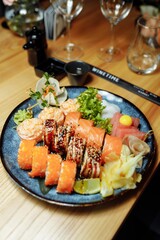 Mixed Sushi Set nigiri, rolls and sashimi served in traditional Japan black Sushioke round plate.