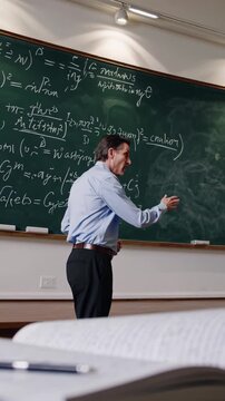 Math professor teaching a lecture in a classroom, writing complex equations on a large blackboard, with an open textbook and pen on a desk in the foreground