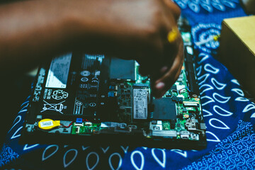 Close-up of hands repairing a laptop's motherboard in India, sho