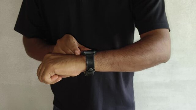 Indian person touch smart watch for tracking gym workout and physical exercise. Young technology enthusiast athlete man monitoring daily fitness training performance and progress. Closeup side view.