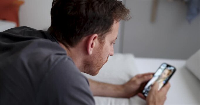 guy doom scrolling through social media or waiting for a message. Alone in bedroom, staring at smartphone. emotional distance psychological strain. Smartphone addiction. Digital overload, loneliness.
