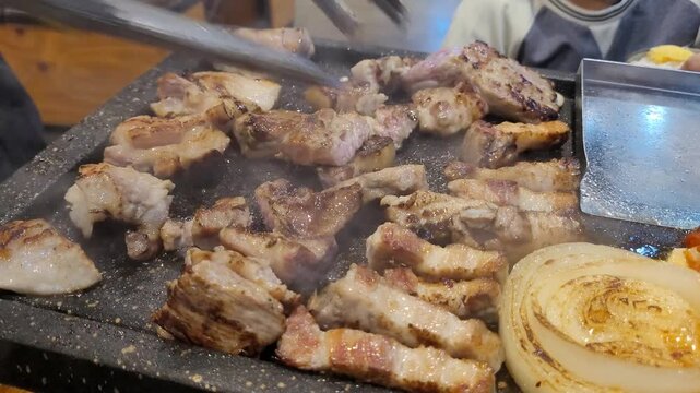 달궈진 석쇠 불판 위에서 노릇하게 익어가는 한국식 삼겹살 구이