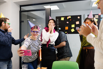Business team celebrates success with fun party in modern office, featuring decorations and joyful colleagues enjoying treats and sparklers