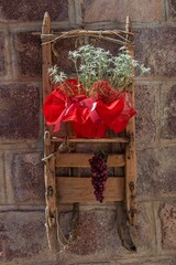 Decorative wooden sled with edelweiss and hanging grape cluster