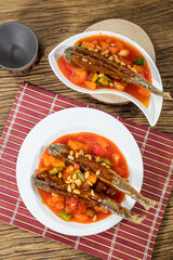 Two plates of whole fish cooked in sweet and sour sauce with colorful diced vegetables served on bamboo mats.