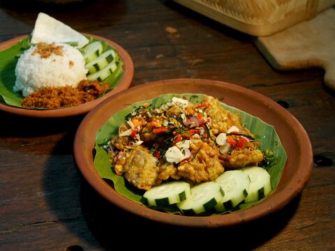 Popular Indonesian Ayam Geprek featuring crispy fried chicken smashed with fresh spicy chili sambal, served with rice on a traditional banana leaf