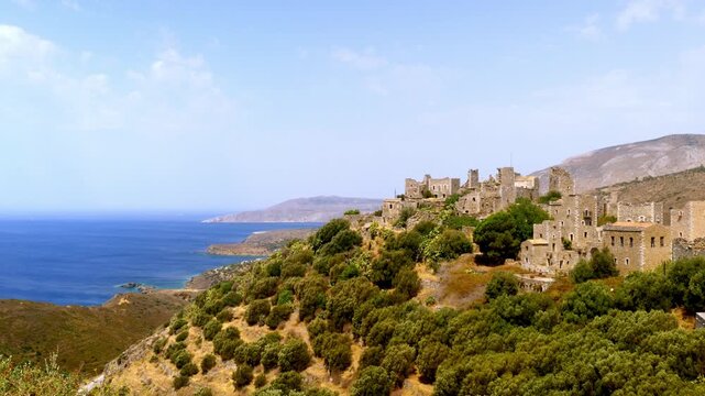 Historic stone village overlooking the Mediterranean Sea in Mani, Greece. Traditional coastal architecture and rugged landscape of the Peloponnese region under a bright summer sky