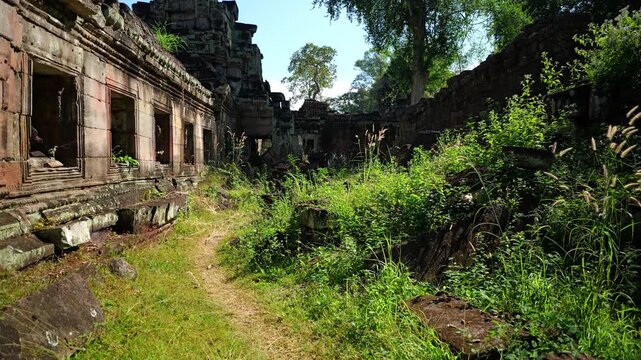 Walking through Preah Khan Temple ruins past stone windows and an overgrown courtyard path in Siem Reap