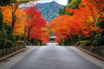 A serene autumn scene with vibrant red, orange, and yellow leaves lining a winding road that leads to a majestic mountain in the distance.