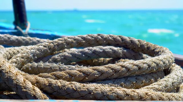 A coiled rope on a boat deck with a blurred turquoise sea background