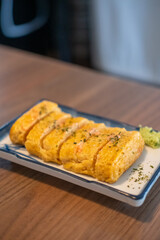Tamagoyaki, a Japanese omelette made by rolling together several layers of fried beaten eggs, served on a plate.