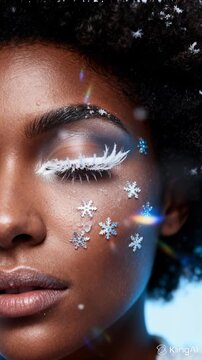 woman with dark skin and expressive brown eyes, adorned with sparkling snowflake stickers around her eyes, in blurred light blue holiday setting, serene and elegant, winter celebration