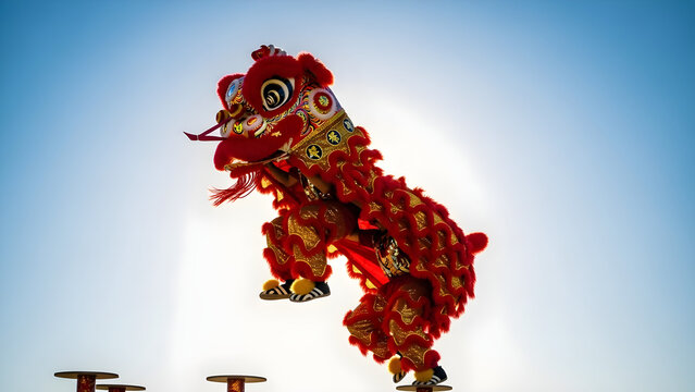 Red Chinese Lion Dance Jumping in Mid Air Against Clear Blue Sky