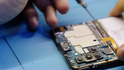 Close up of a technician repairing a mobile phone circuit board