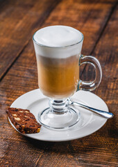 Latte macchiato with layered milk and foam on wooden table