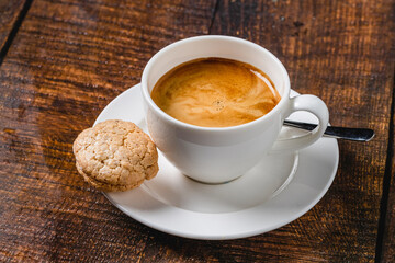 Freshly brewed espresso served with cookie on wooden table