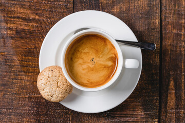 Freshly brewed espresso served with cookie on wooden table