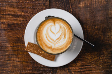 Caffe latte with leaf latte art served on wooden table