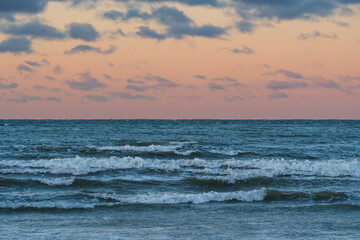 Obraz premium Beautiful scenic view of rolling waves on the Baltic Sea coast in Tallinn Estonia during a dramatic sunset with clouds.
