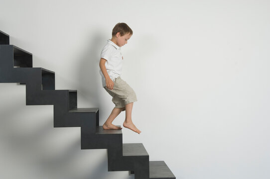 Boy running down modern stair indoors with white wall background